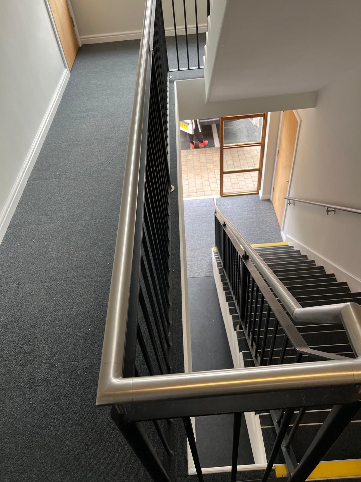 Stairwell with carpeted floor, metal railing, and a doorway at the bottom.
