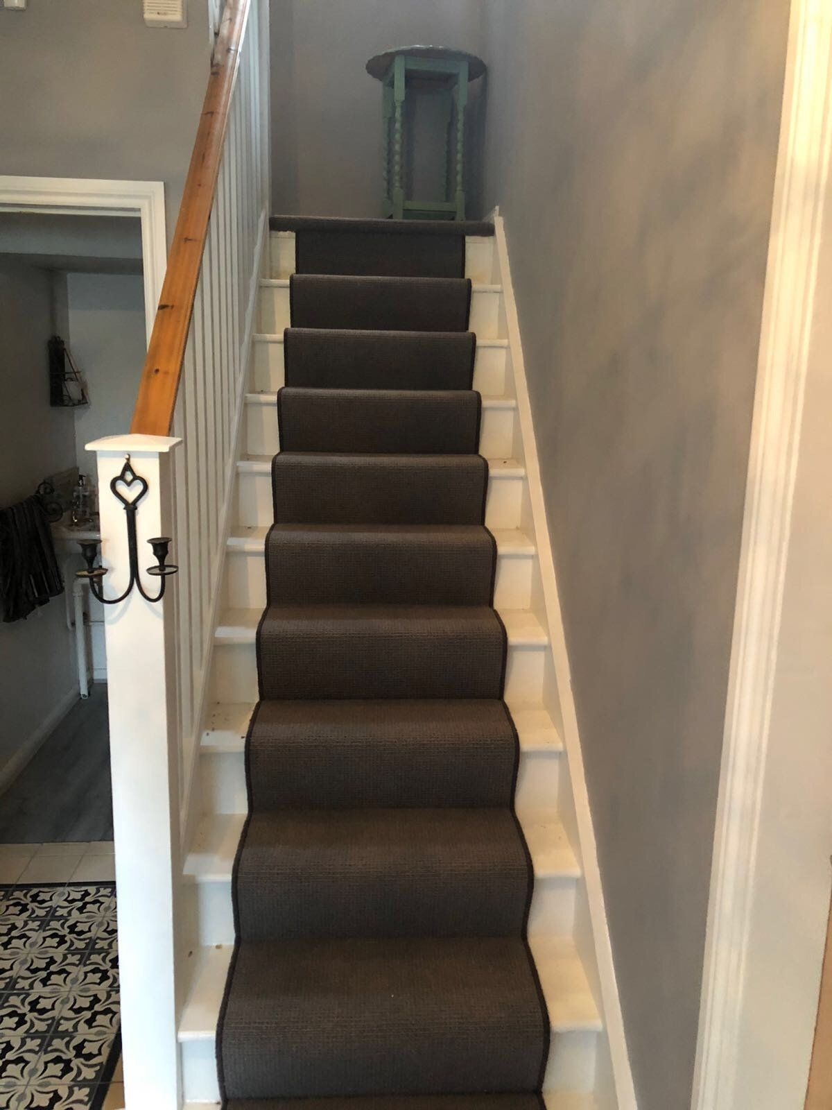 A staircase with a gray carpet and a white railing