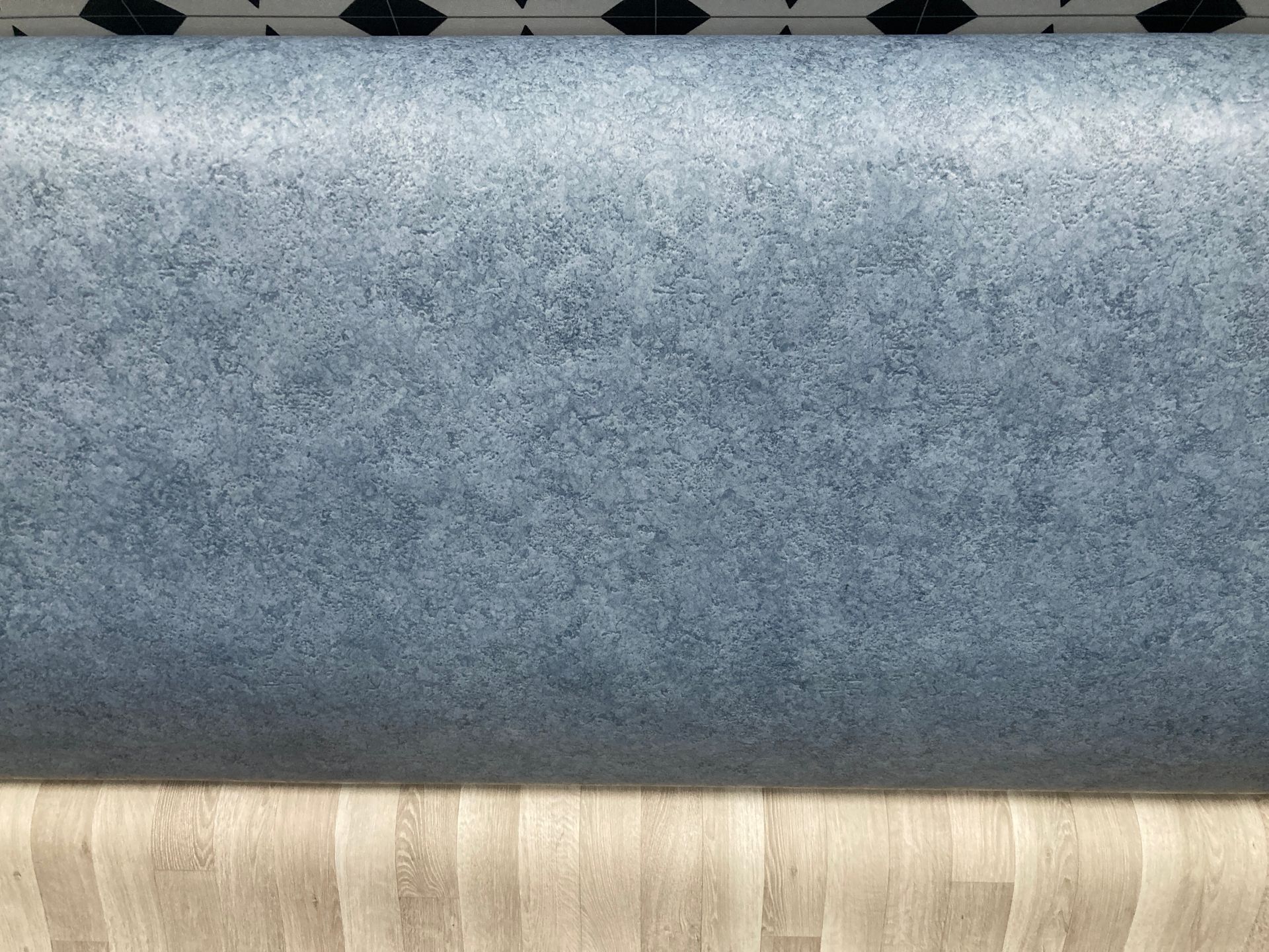A roll of vinyl flooring is sitting on top of a wooden floor.