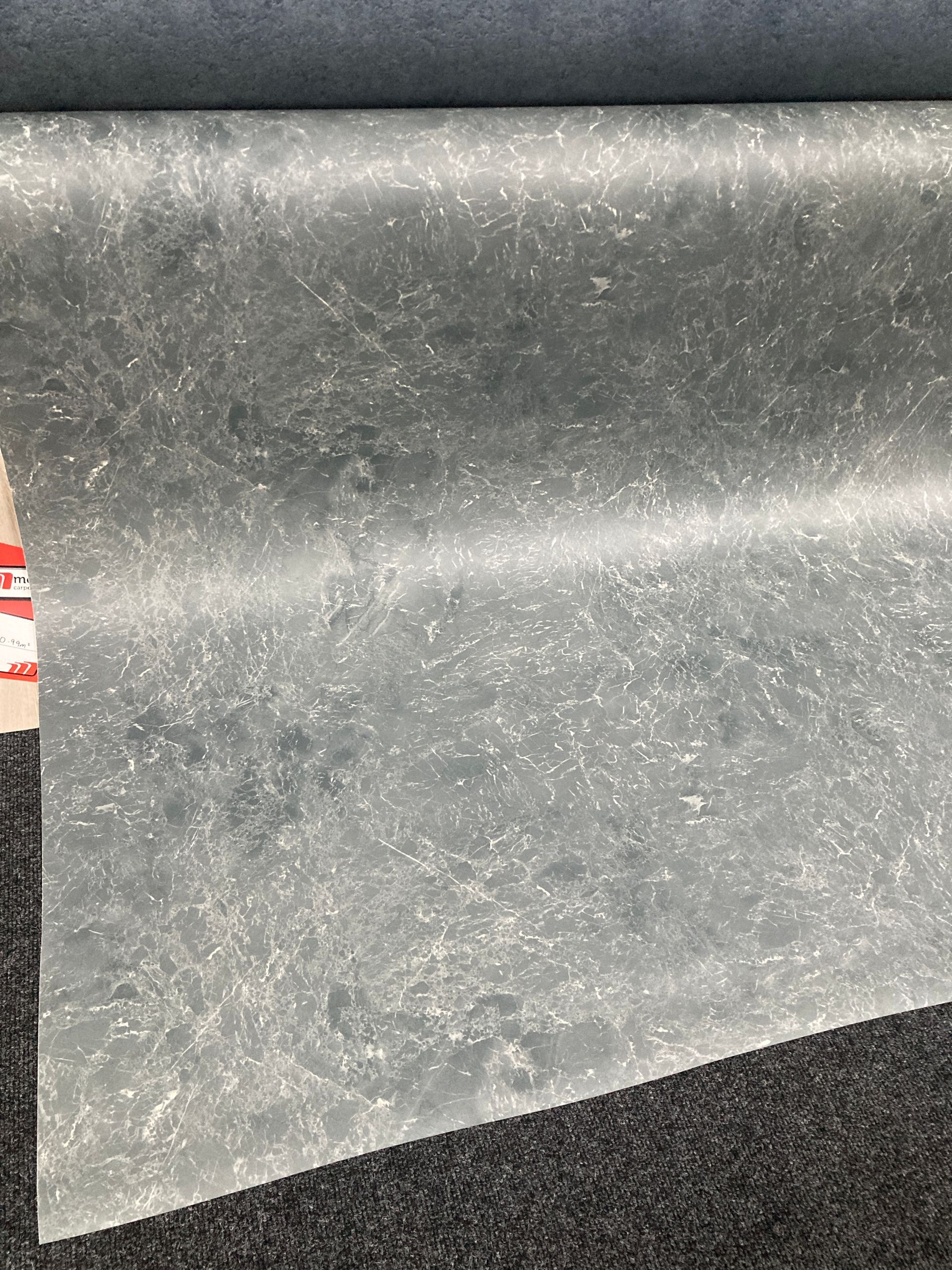 A roll of carpet is sitting on top of a black carpet.