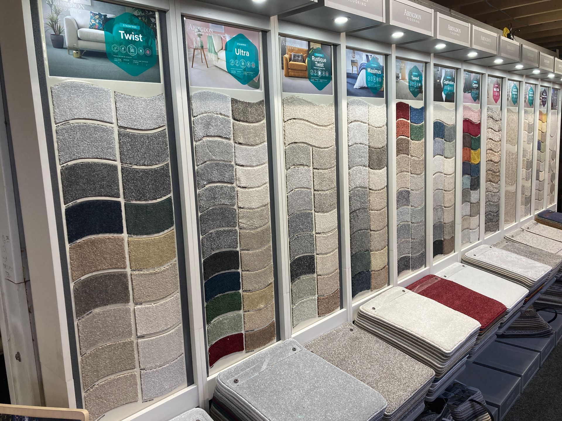 A flooring showroom display wall featuring various carpet texture and color swatches arranged in vertical panels.