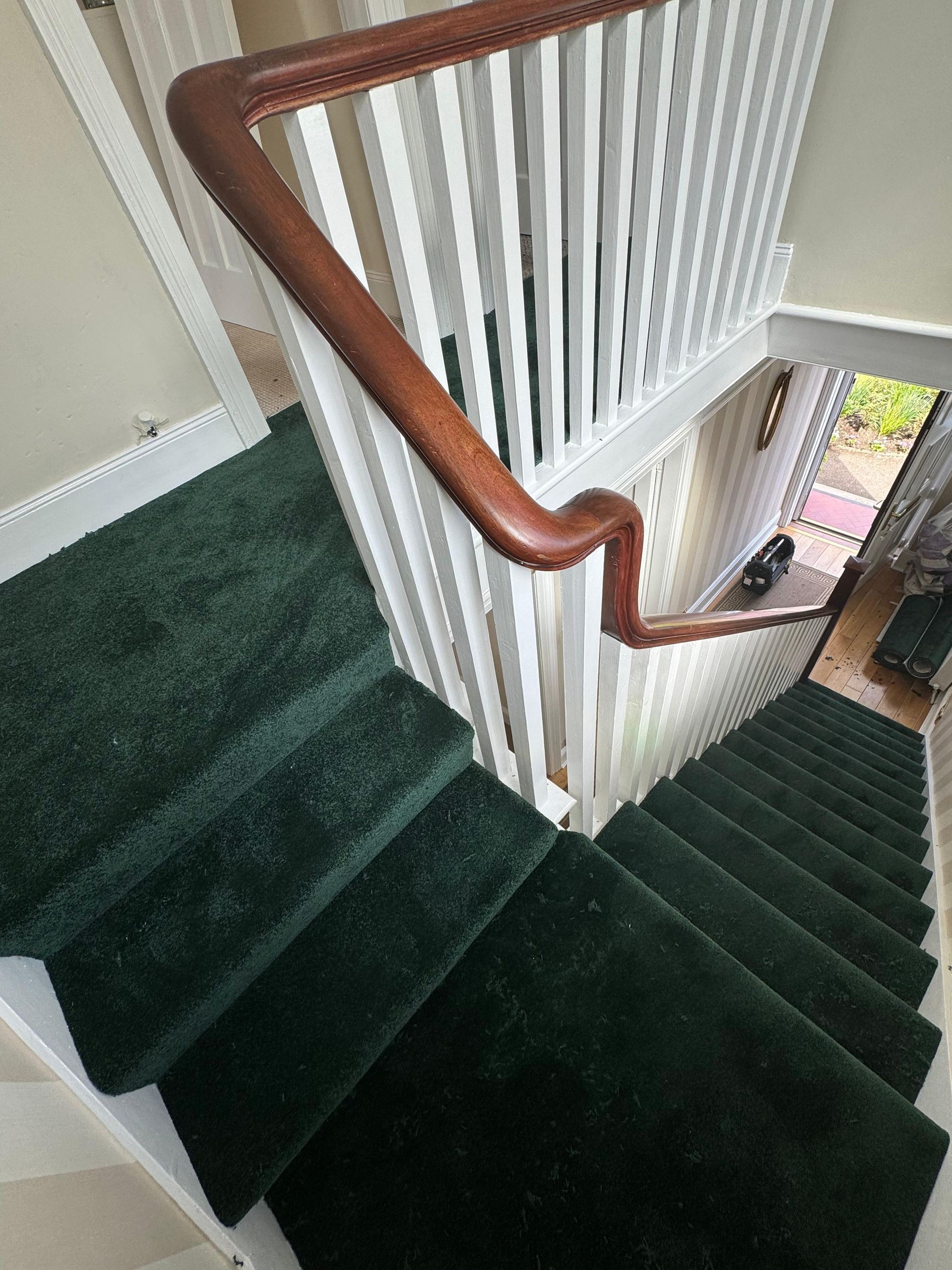 A staircase with green carpet and a wooden railing.