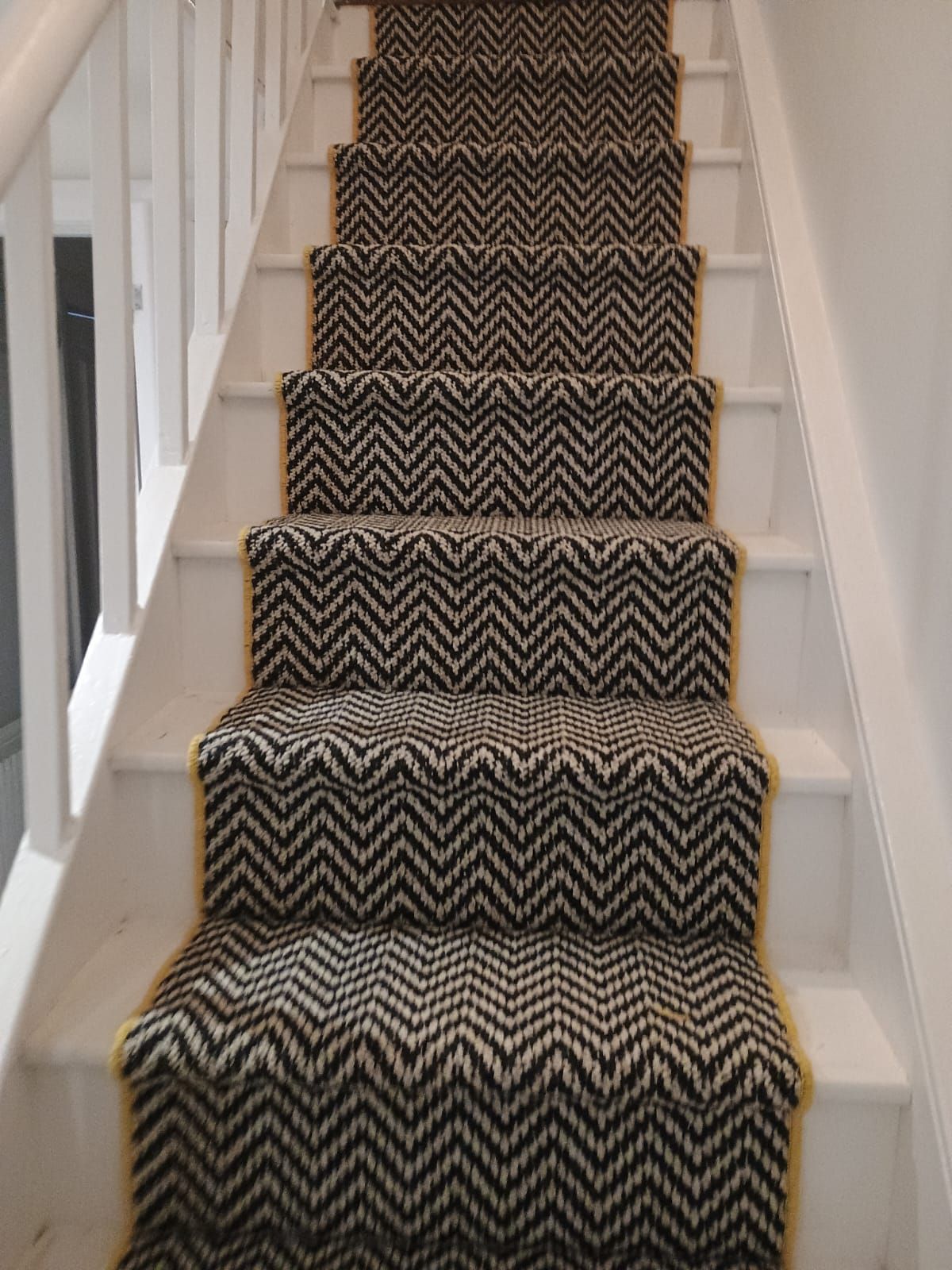 A staircase with a black and white carpet on it.