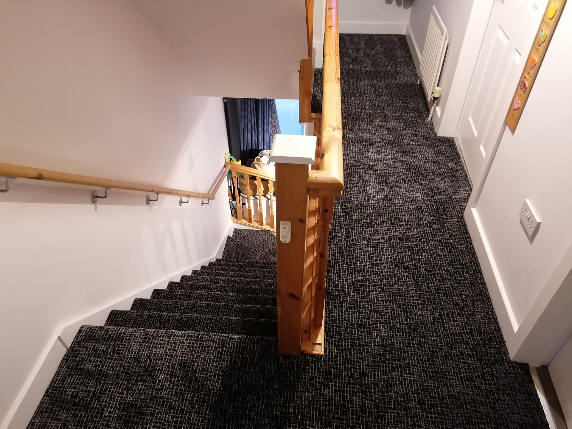 A staircase with a black carpet and a wooden railing
