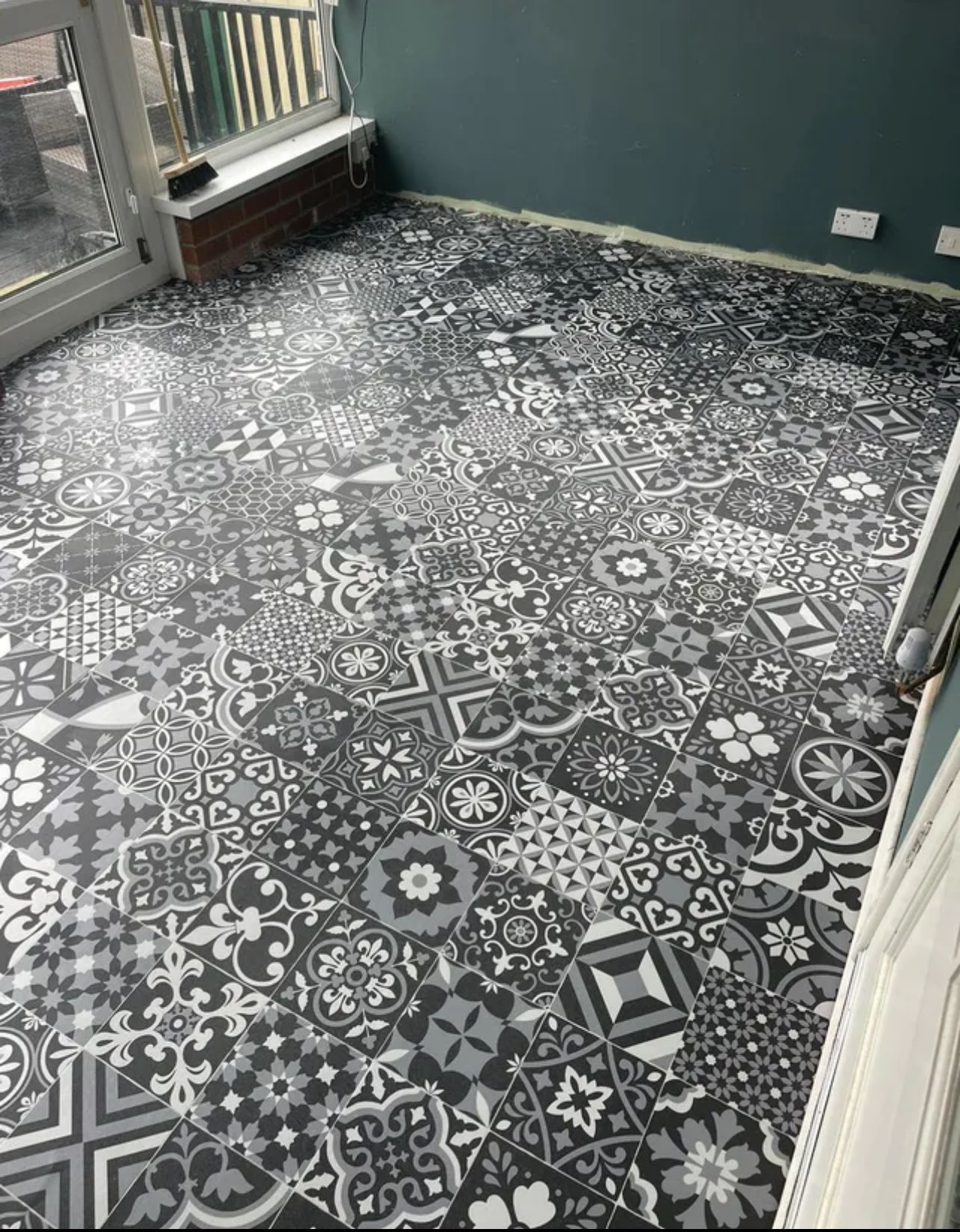 A black and white tile floor in a room with a window.