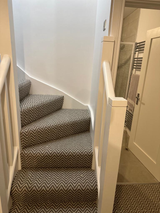 A spiral staircase with a carpeted staircase and a white railing.