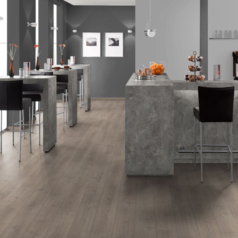 Modern interior showing bar-height counters and tables on a light wood-look floor, with black stools in a minimalist room.