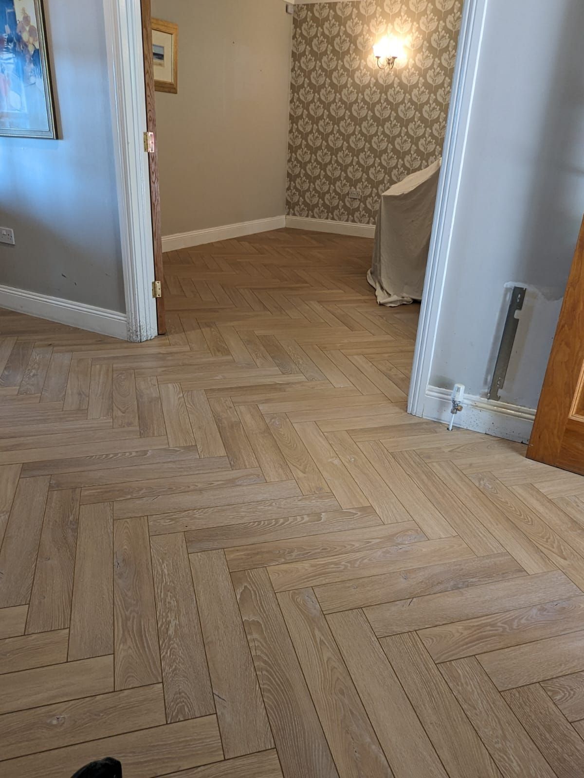 A wooden floor with a herringbone pattern in a room.