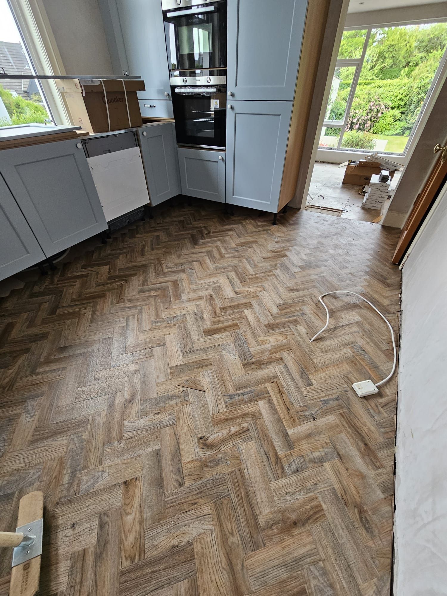 A kitchen with a wooden floor in a herringbone pattern.
