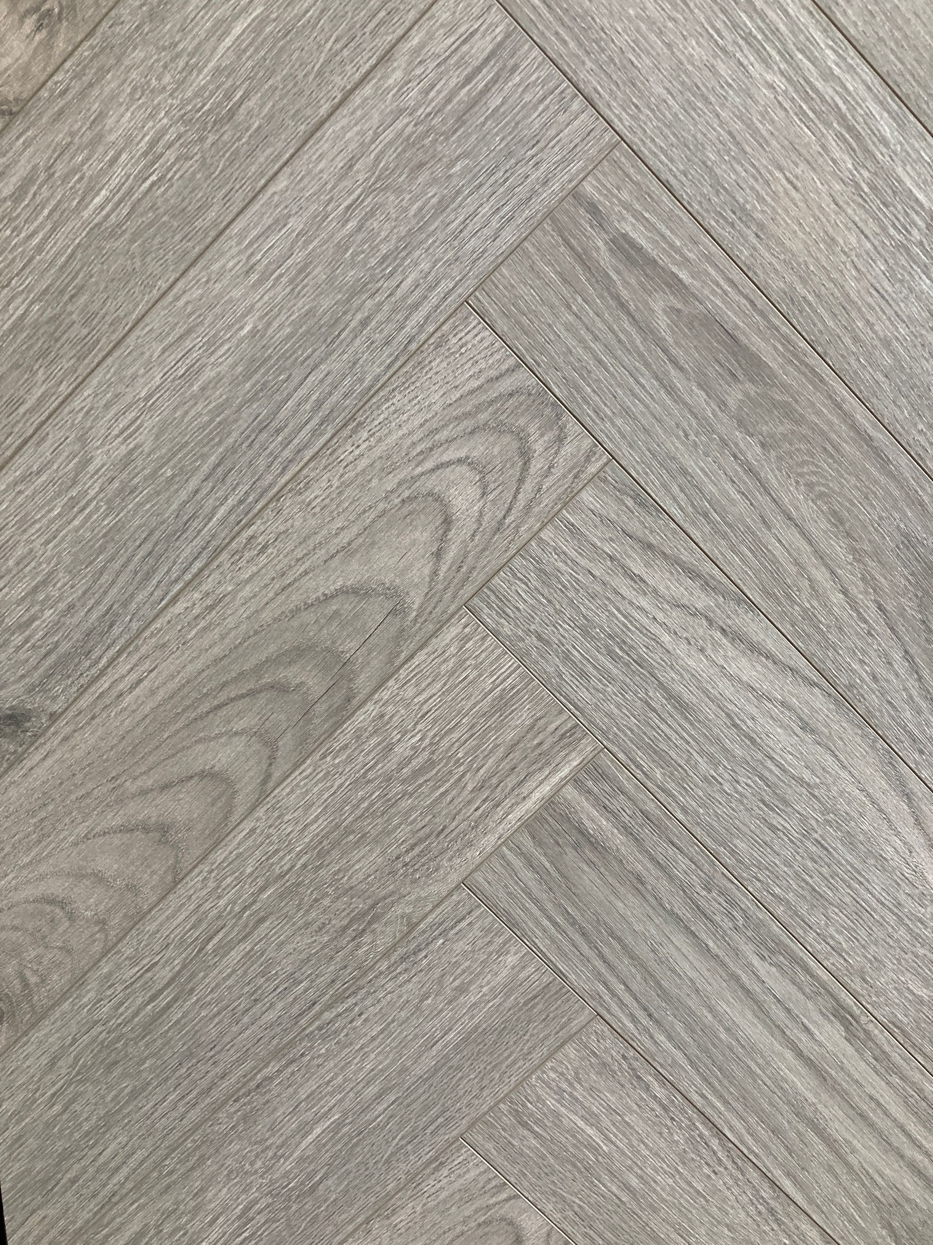 A close up of a gray wooden floor in a herringbone pattern.