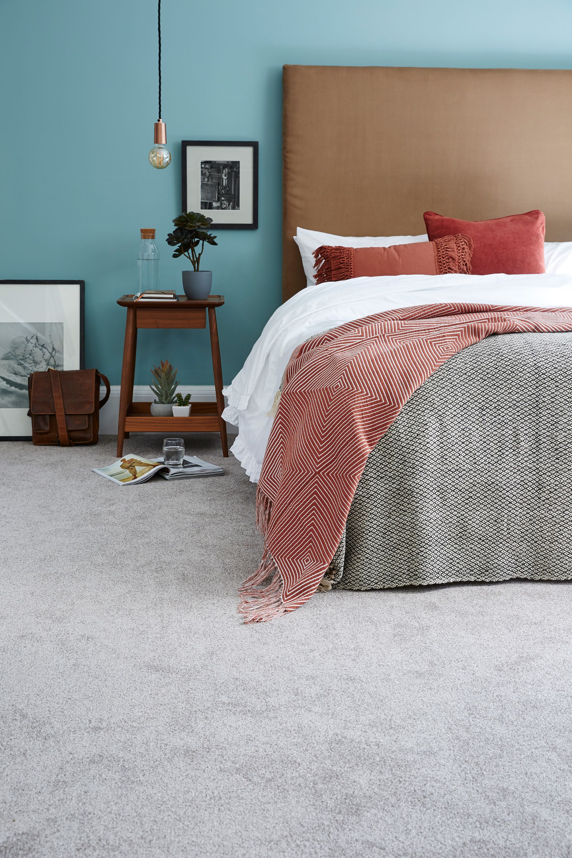 A bedroom with a bed , nightstand , and blue walls.