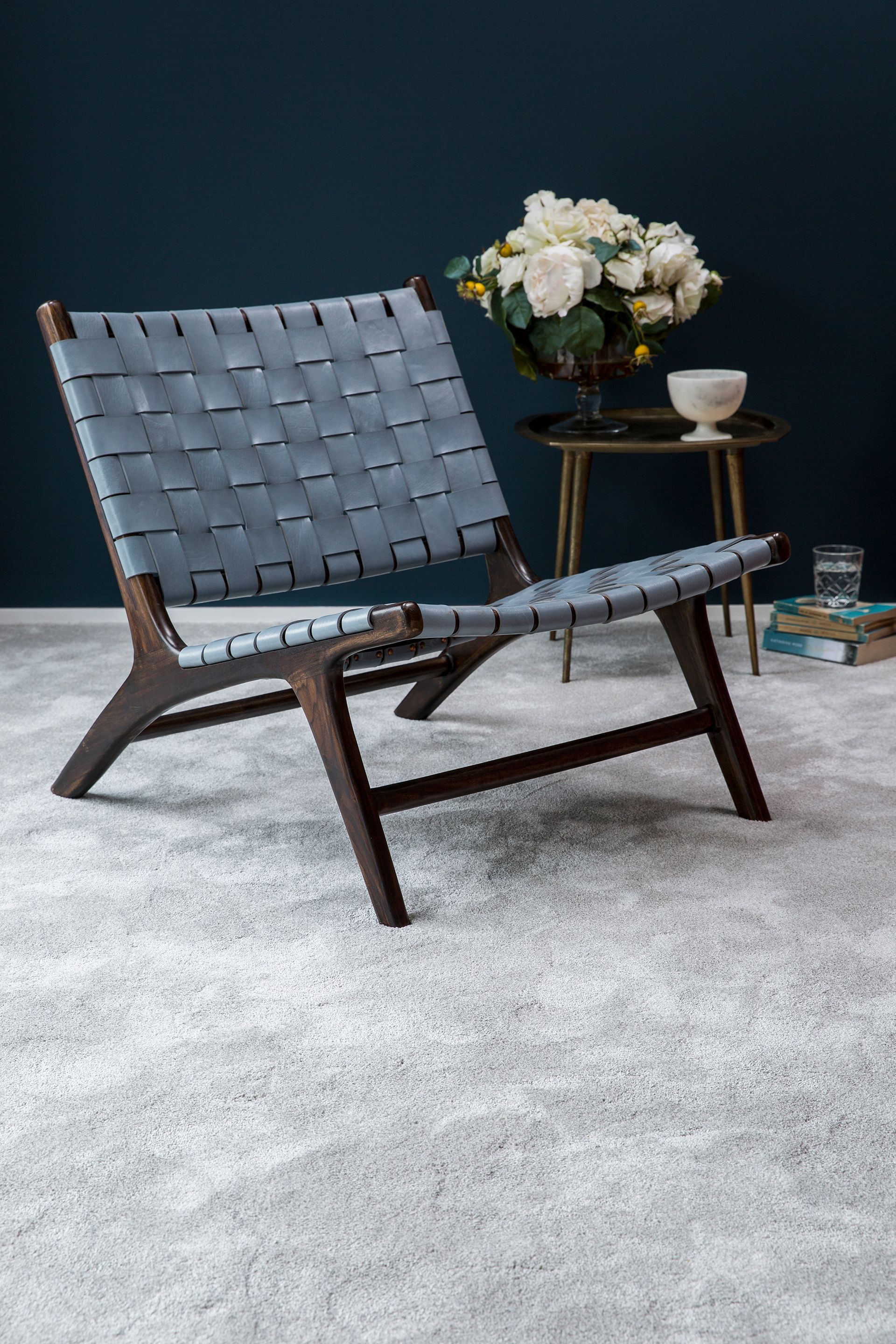 A chair is sitting on a carpet next to a table with flowers on it.