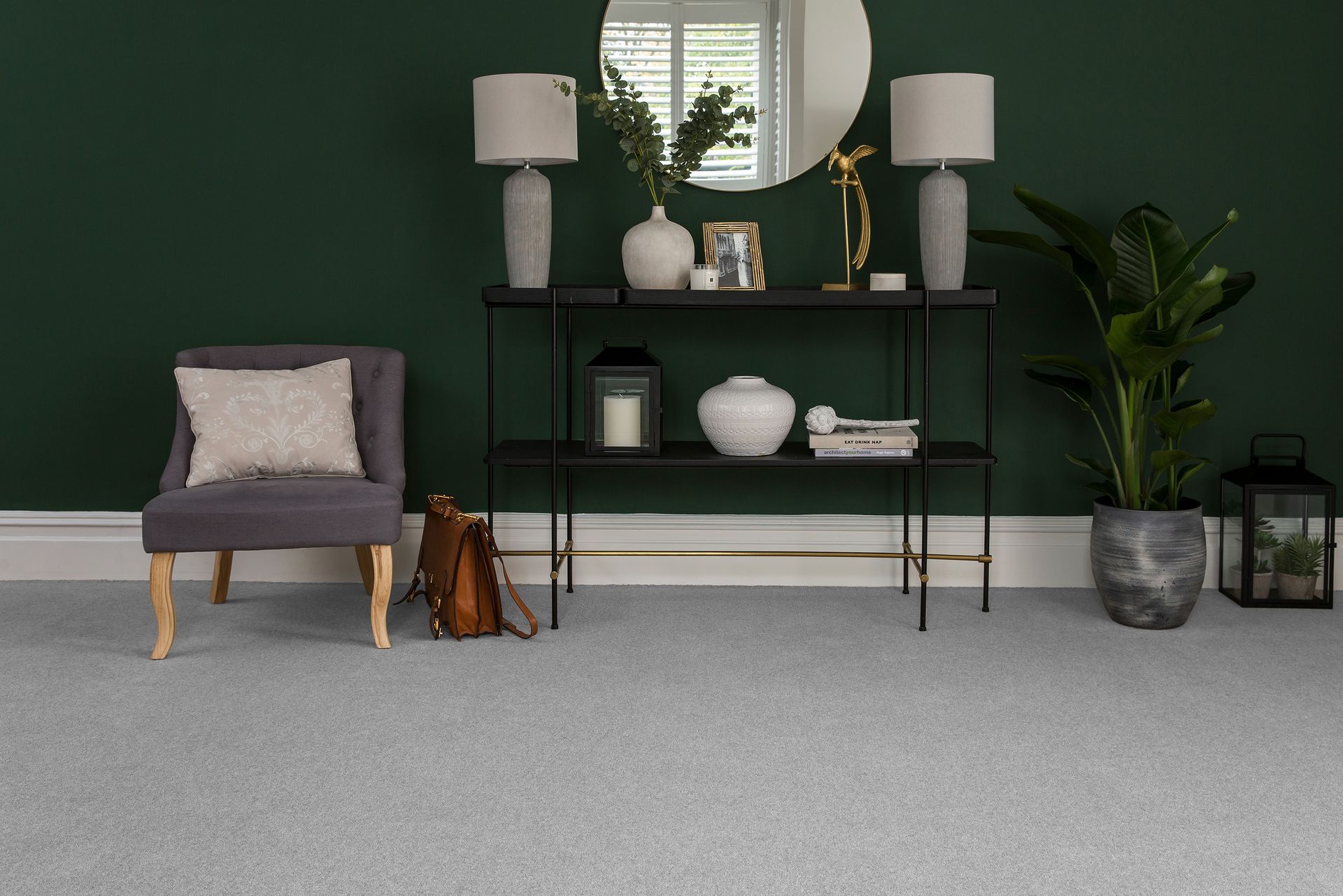 A living room with a chair , table , lamps and a plant.