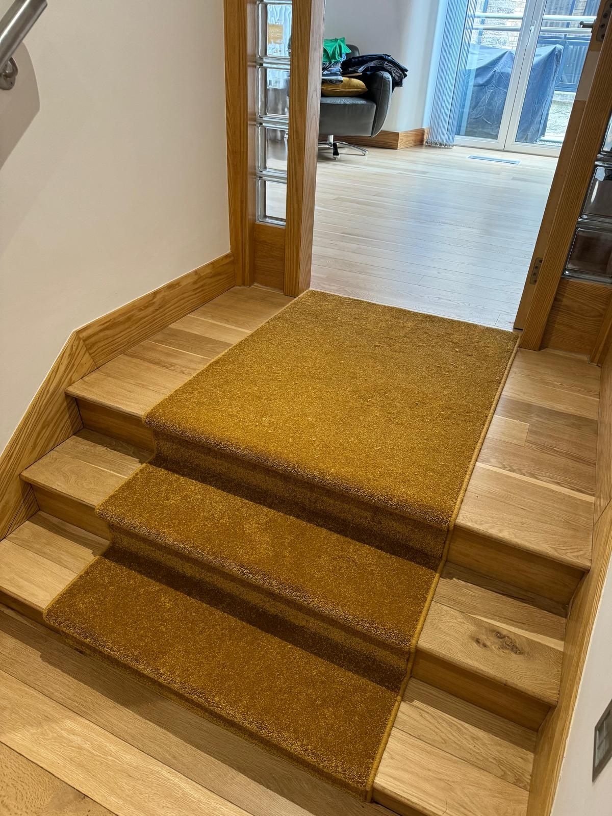 A set of wooden stairs with a yellow rug on the floor.