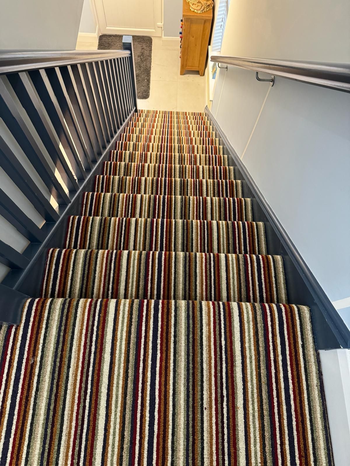 A staircase with a colorful striped carpet on the steps.
