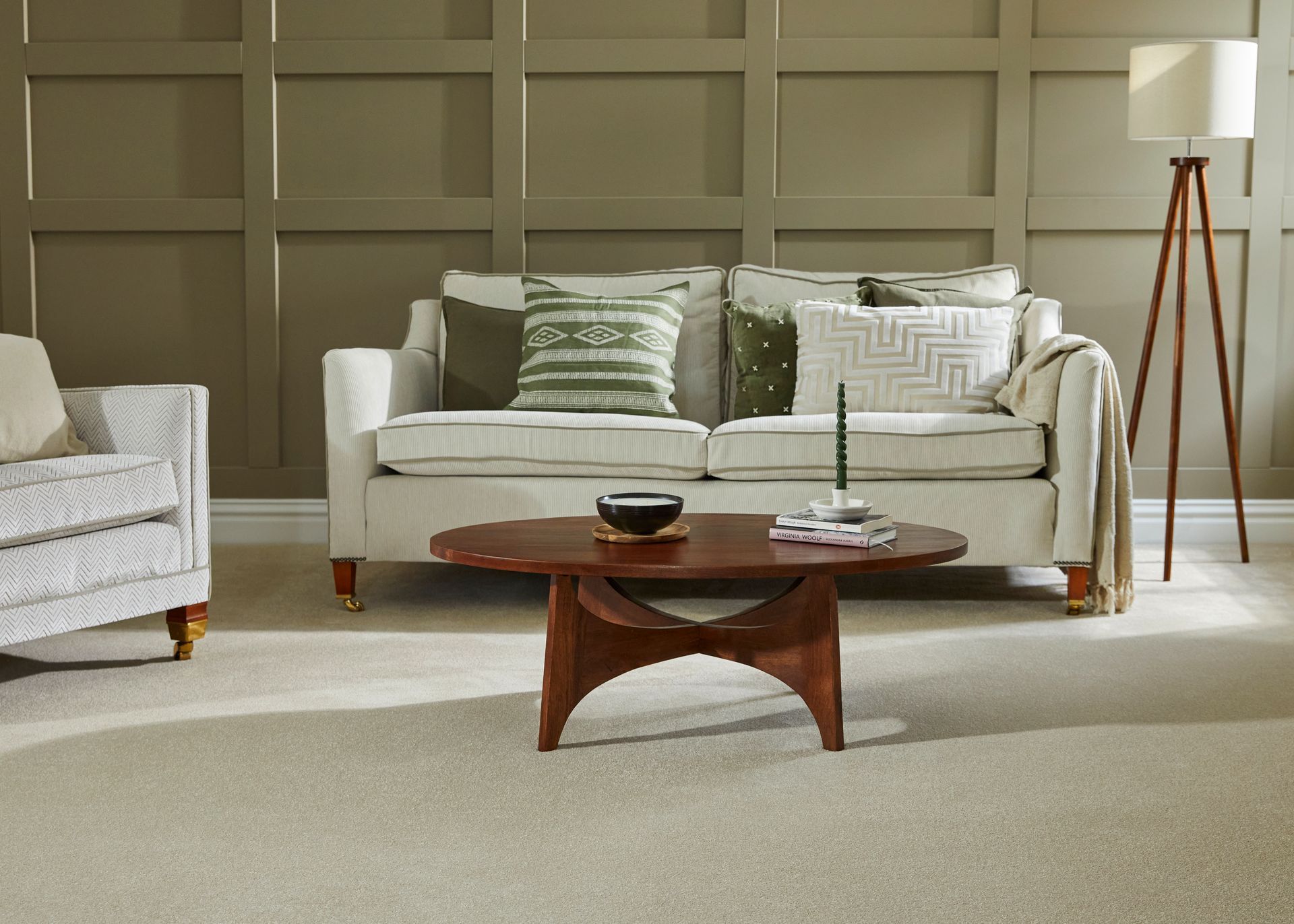 A living room with a couch , chair , coffee table and lamp.