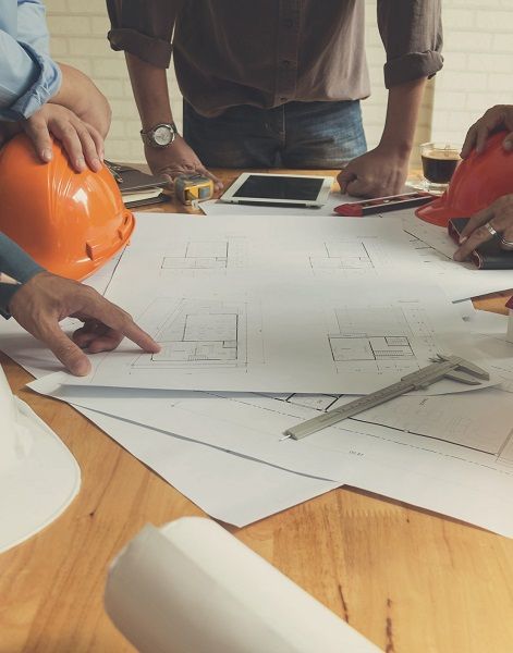 A group of people are sitting around a table looking at a blueprint.