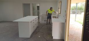 A man in a yellow vest is working in a kitchen.