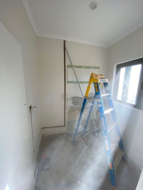 A blue and yellow ladder in a room with a window