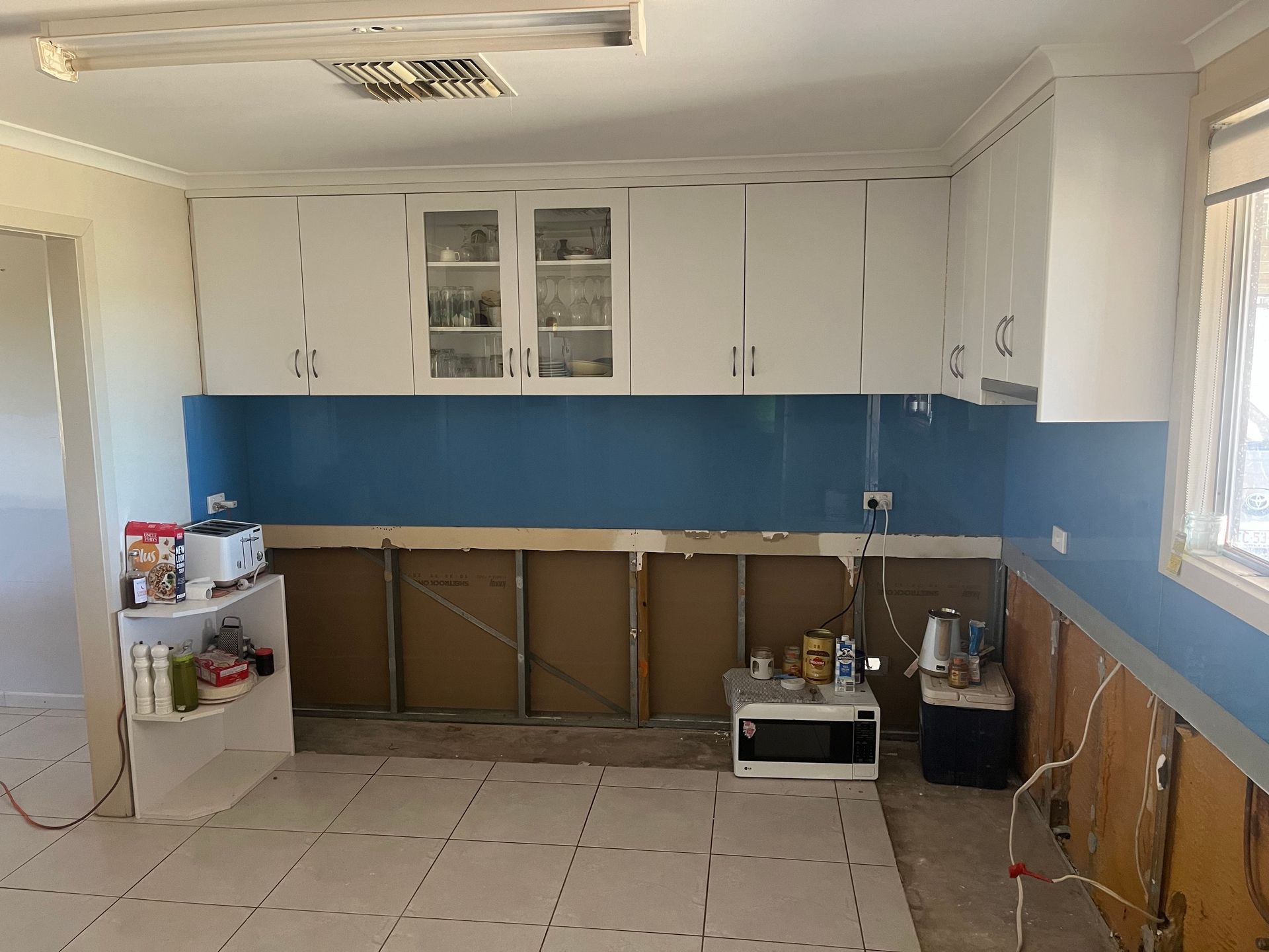 A kitchen with blue walls and white cabinets is being remodelled.