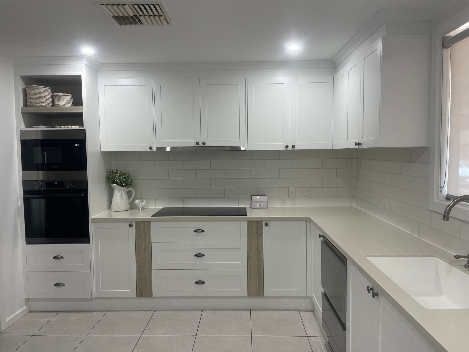 A kitchen with white cabinets , a sink , and a stove.