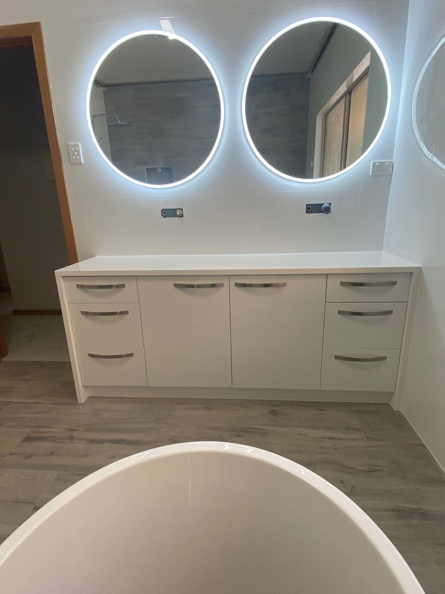 A bathroom with two round mirrors and a bathtub.