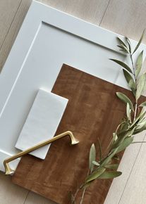 A white cabinet door is sitting on top of a wooden table next to a plant.
