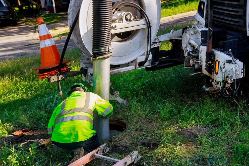 A Man is Kneeling Down in Front of a Vacuum Truck — Bennett's Servicing and Plumbing In Milton, NSW