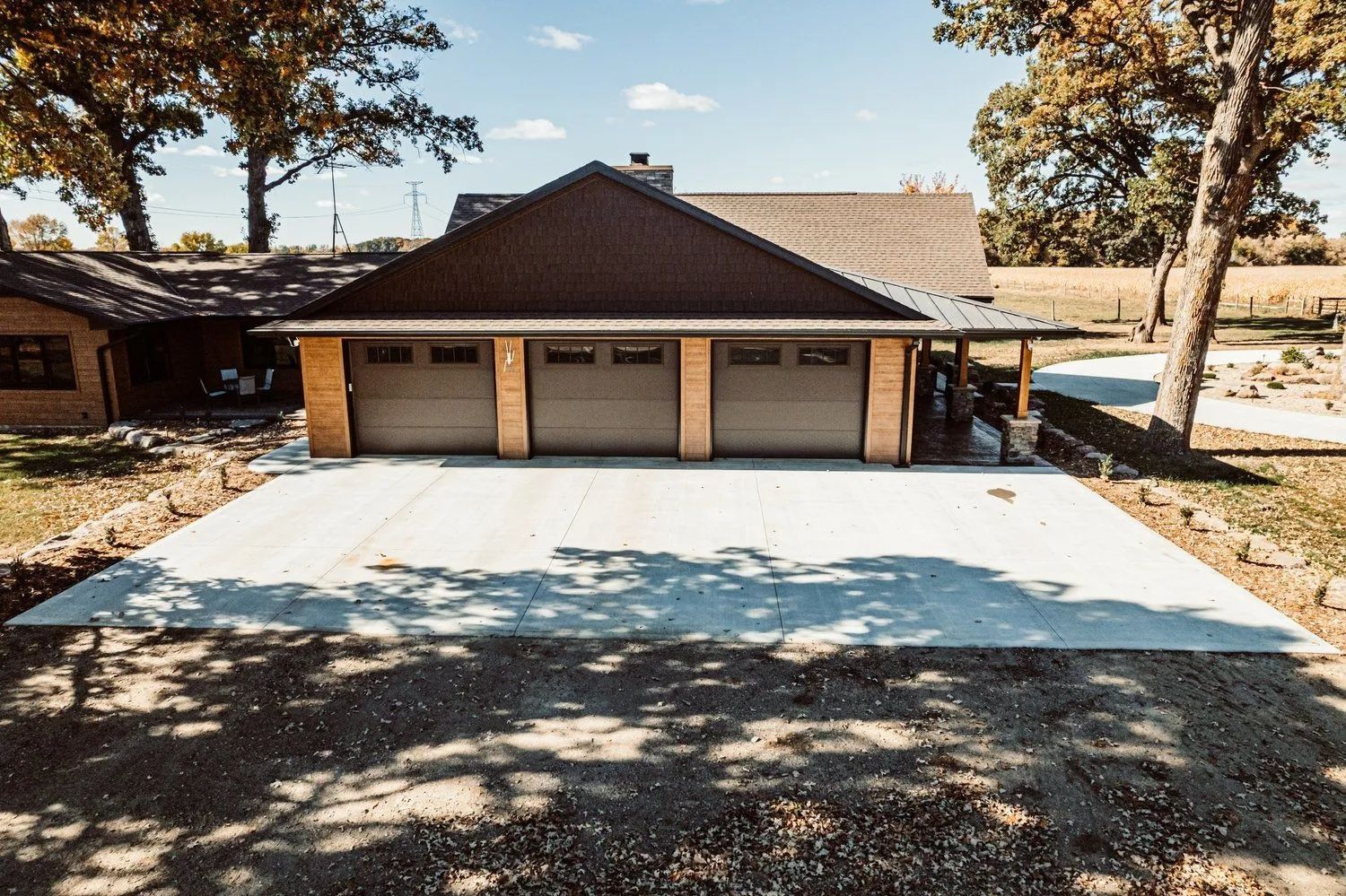 A newly constructed three-bay garage with gray doors, brown roof, and concrete driveway.