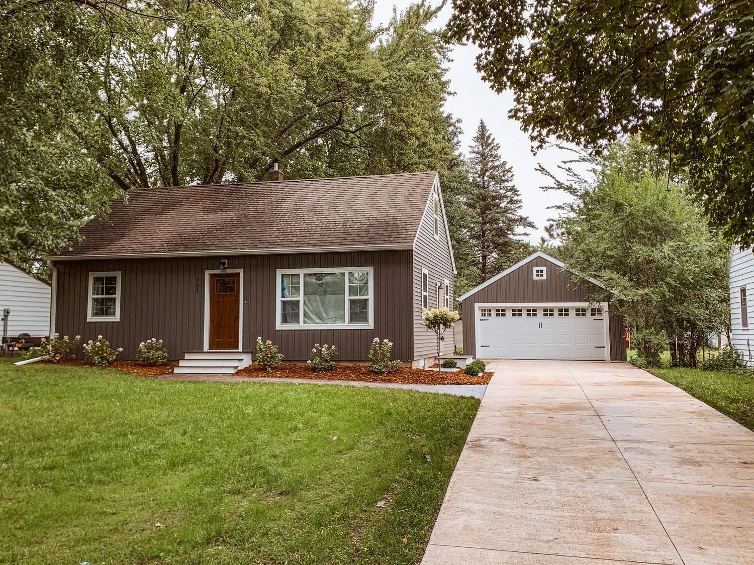 Brown house with a matching garage, brown roof, and concrete driveway.