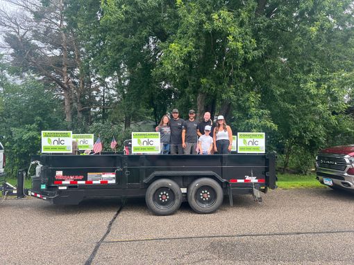 Nagel Landscaping employees standing in a landscape trailer with branded signage.