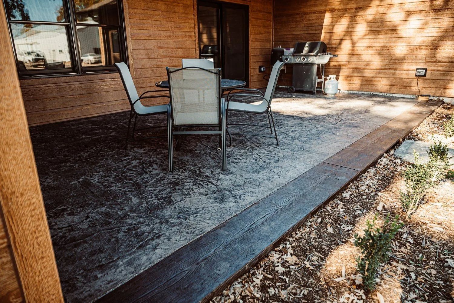 Stamped concrete patio with a table set and grill