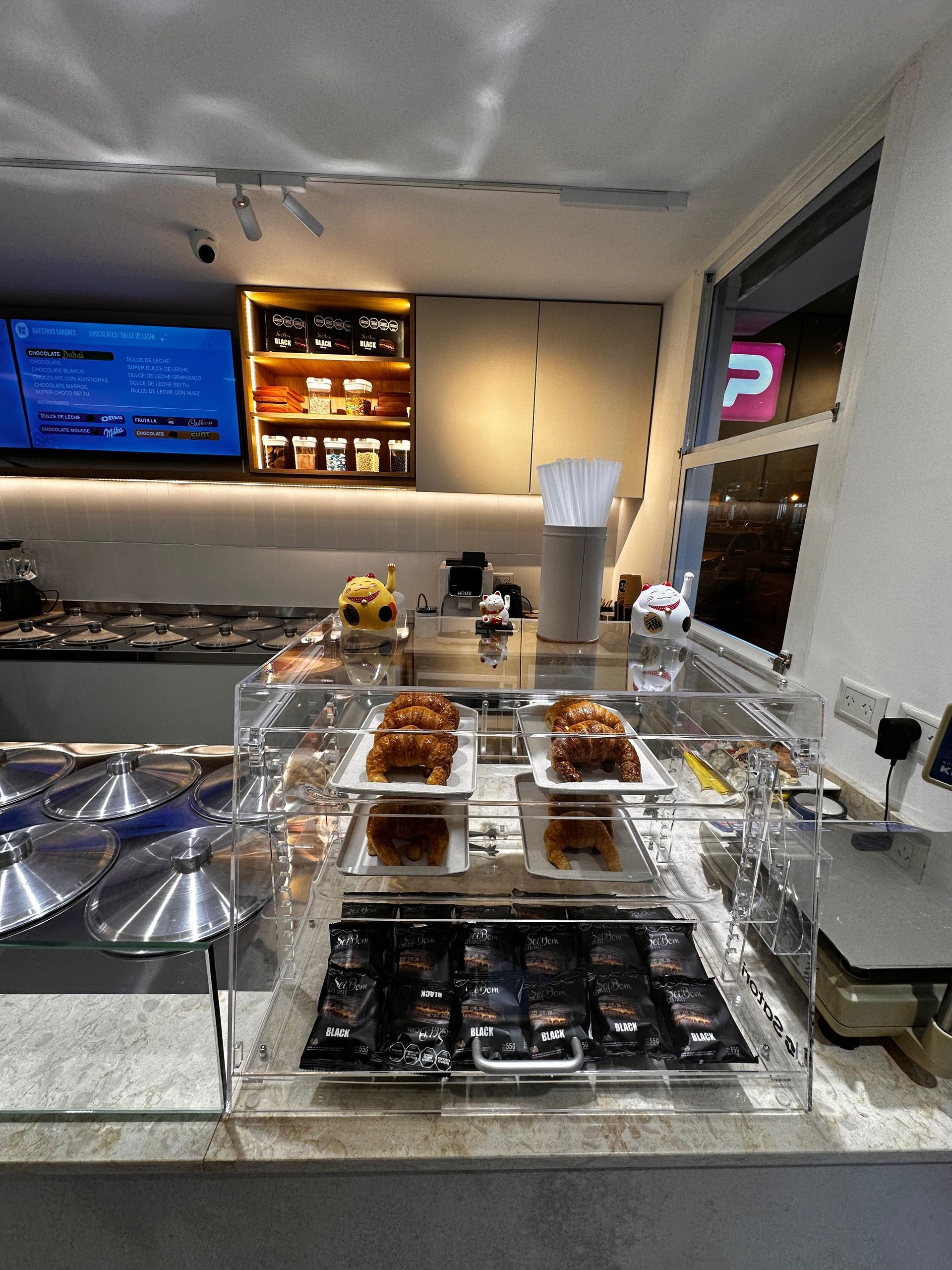 Vitrina de panadería con pasteles y postres variados en una cafetería moderna.