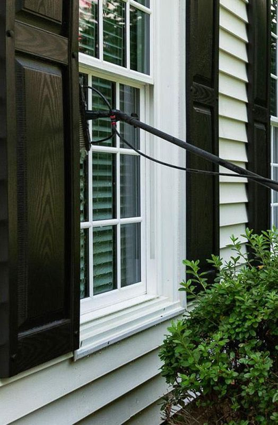 Window with a long-handled cleaning tool reaching across the glass on a house exterior