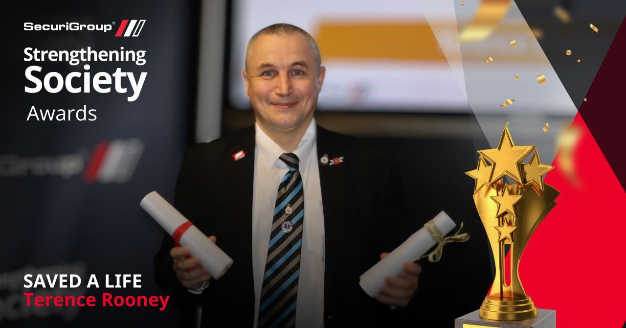 A man holding two certificates beside a trophy for the 