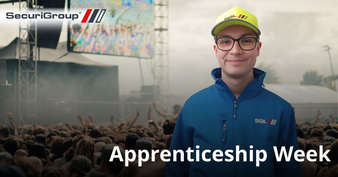 A smiling person in a blue uniform and yellow cap stands before a concert crowd. Text overlay reads: Apprenticeship Week.