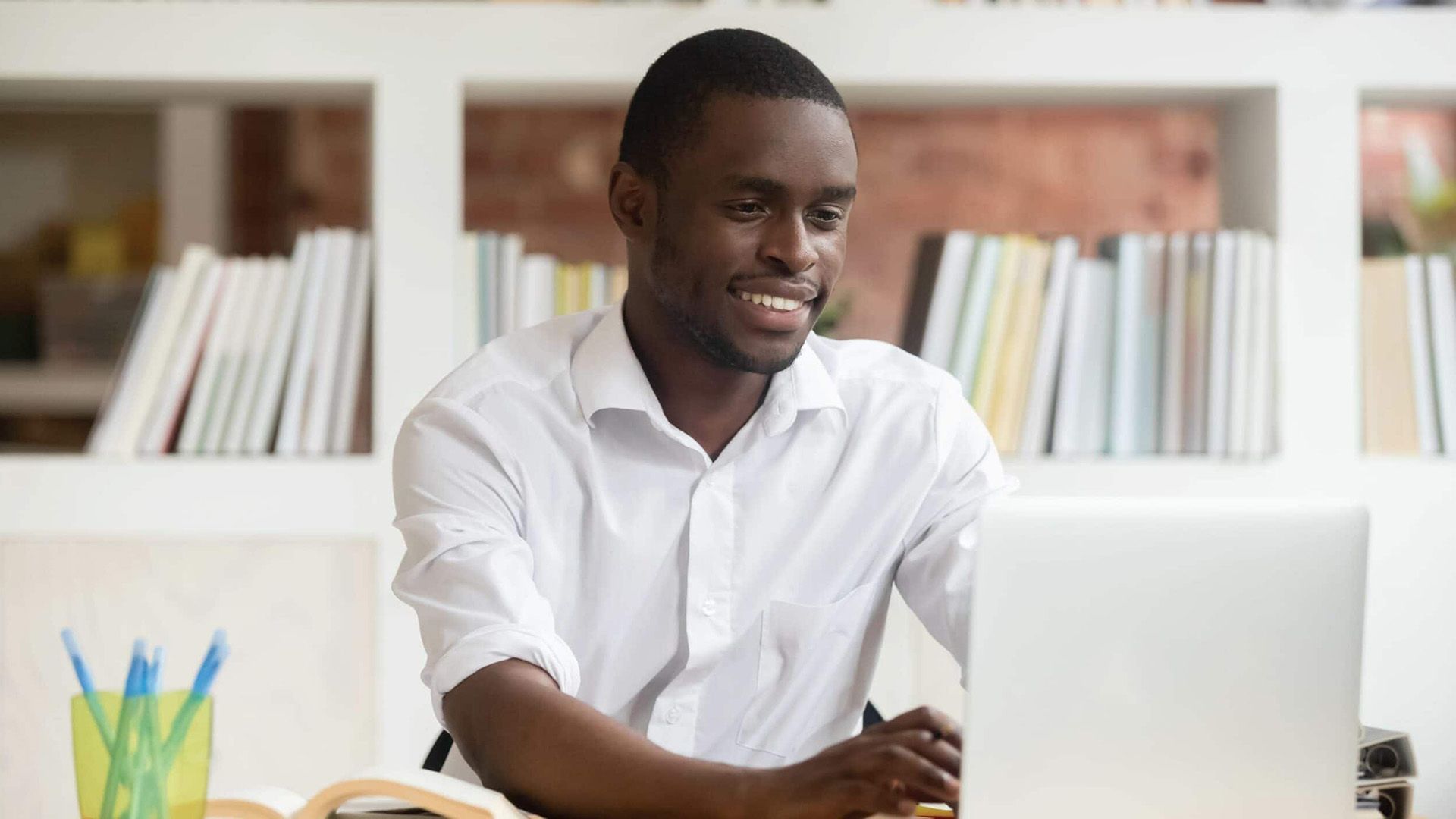 A man is sitting at a desk using a laptop computer.