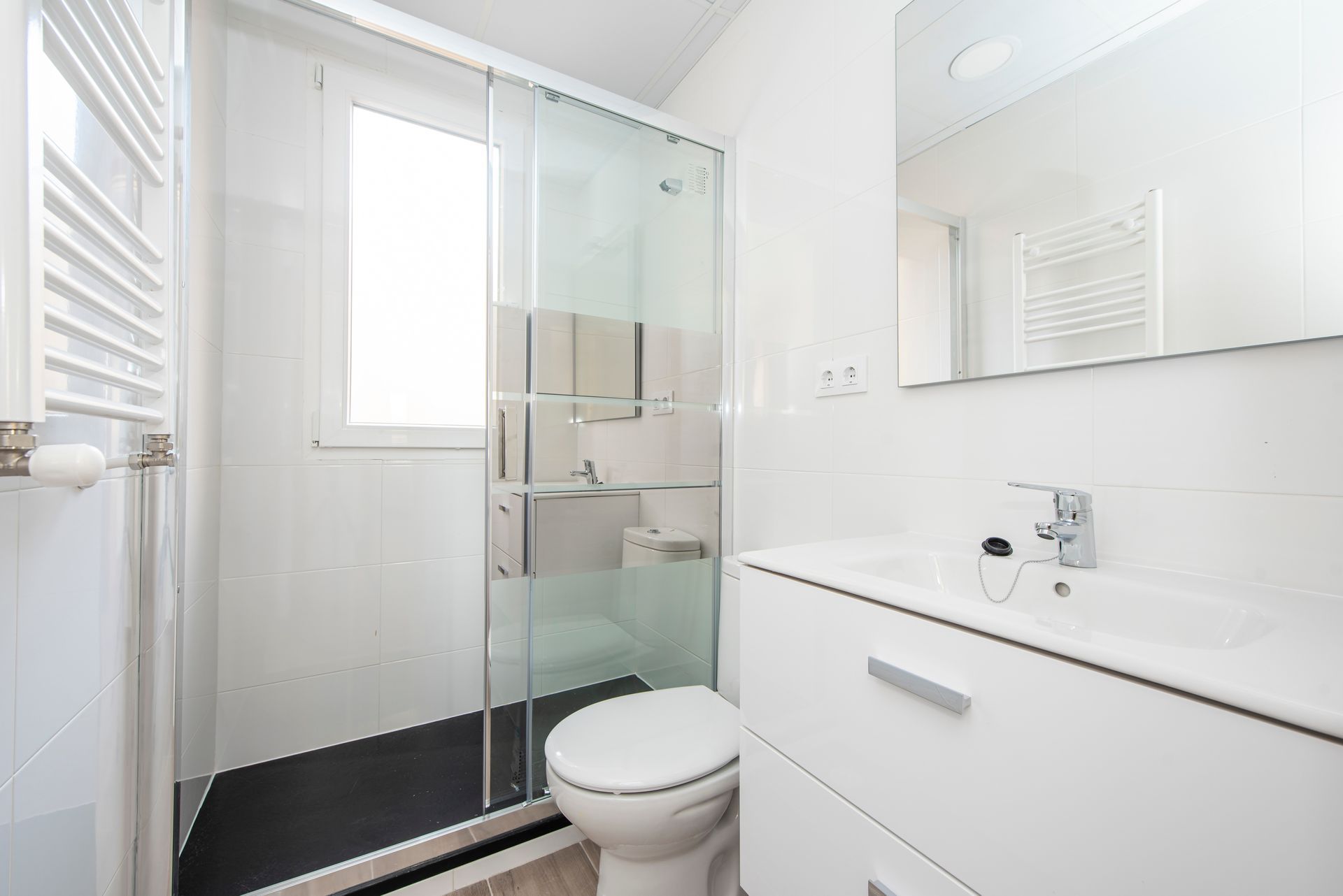 A modern white bathroom with a glass shower door.