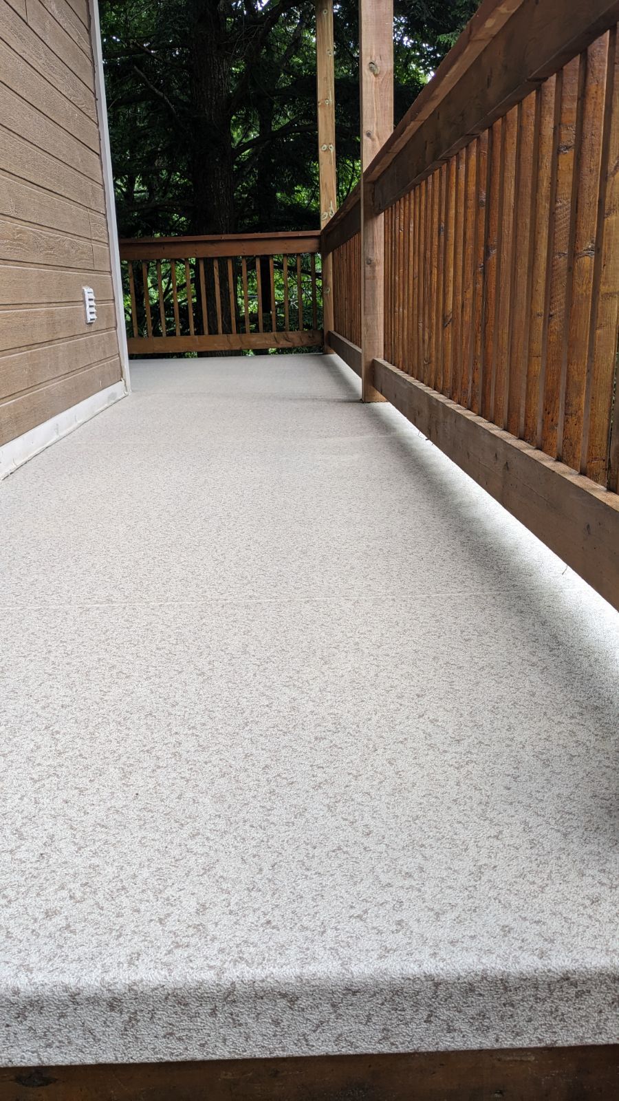 Une terrasse en membrane de PVC avec une balustrade en bois.
