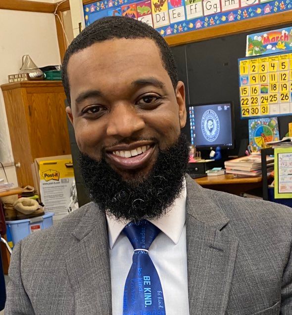 A man with a beard wearing a suit and tie that says be kind