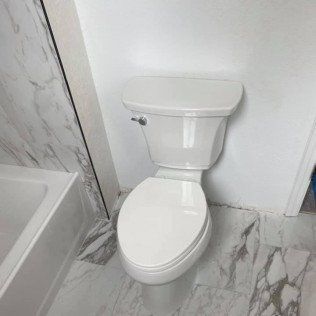 A white toilet is sitting in a bathroom next to a bathtub.