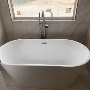 A white bathtub is sitting in a bathroom next to a window.