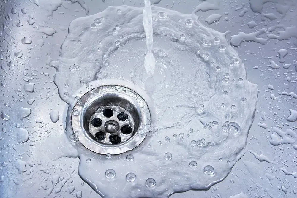 A close up of a sink with water running down the drain.