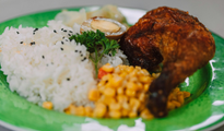 Plate of rice with fried chicken, corn, and garnish on a green tray