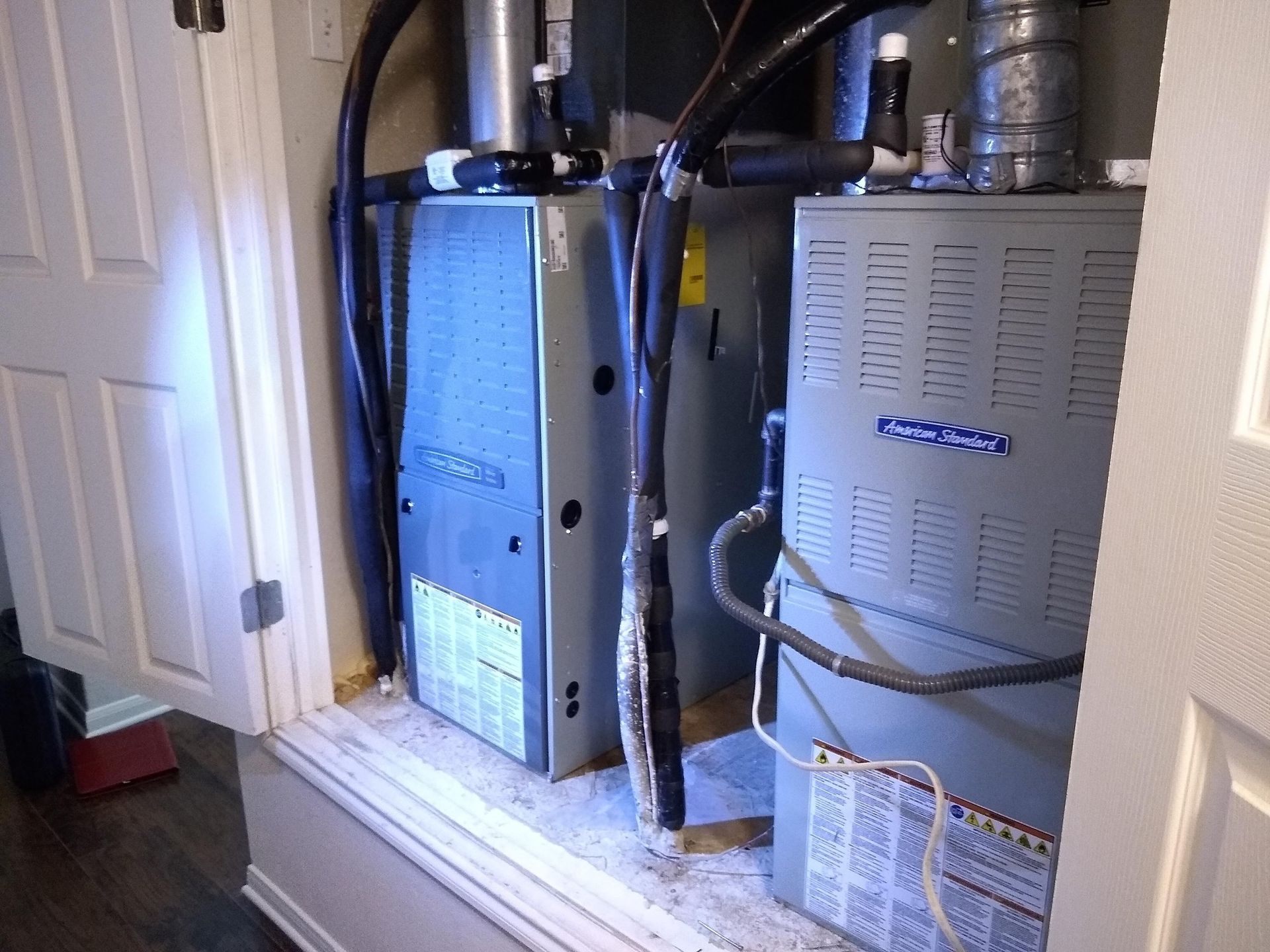 Two furnaces are sitting in a closet next to each other.
