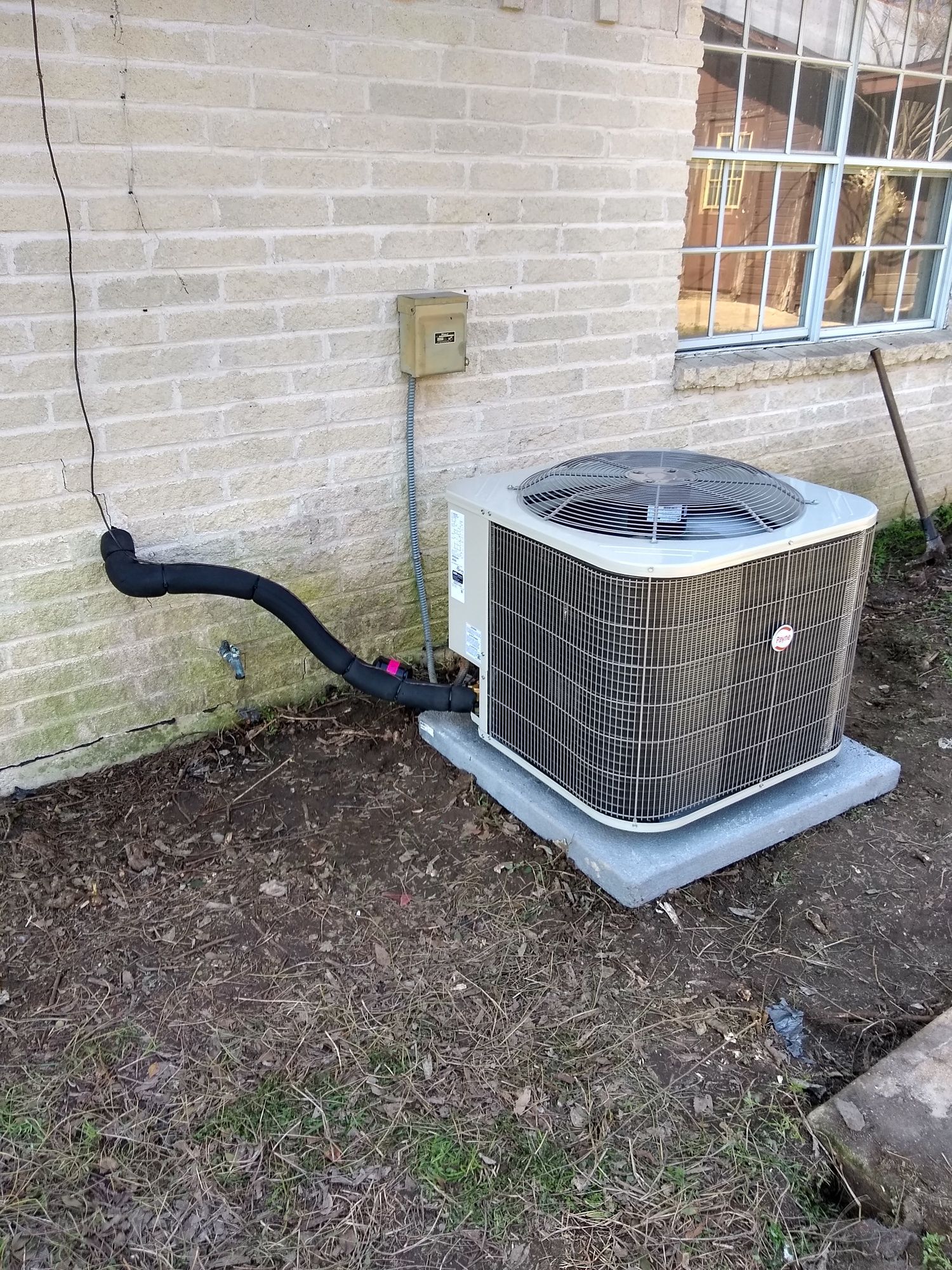 A large air conditioner is sitting outside of a brick building.