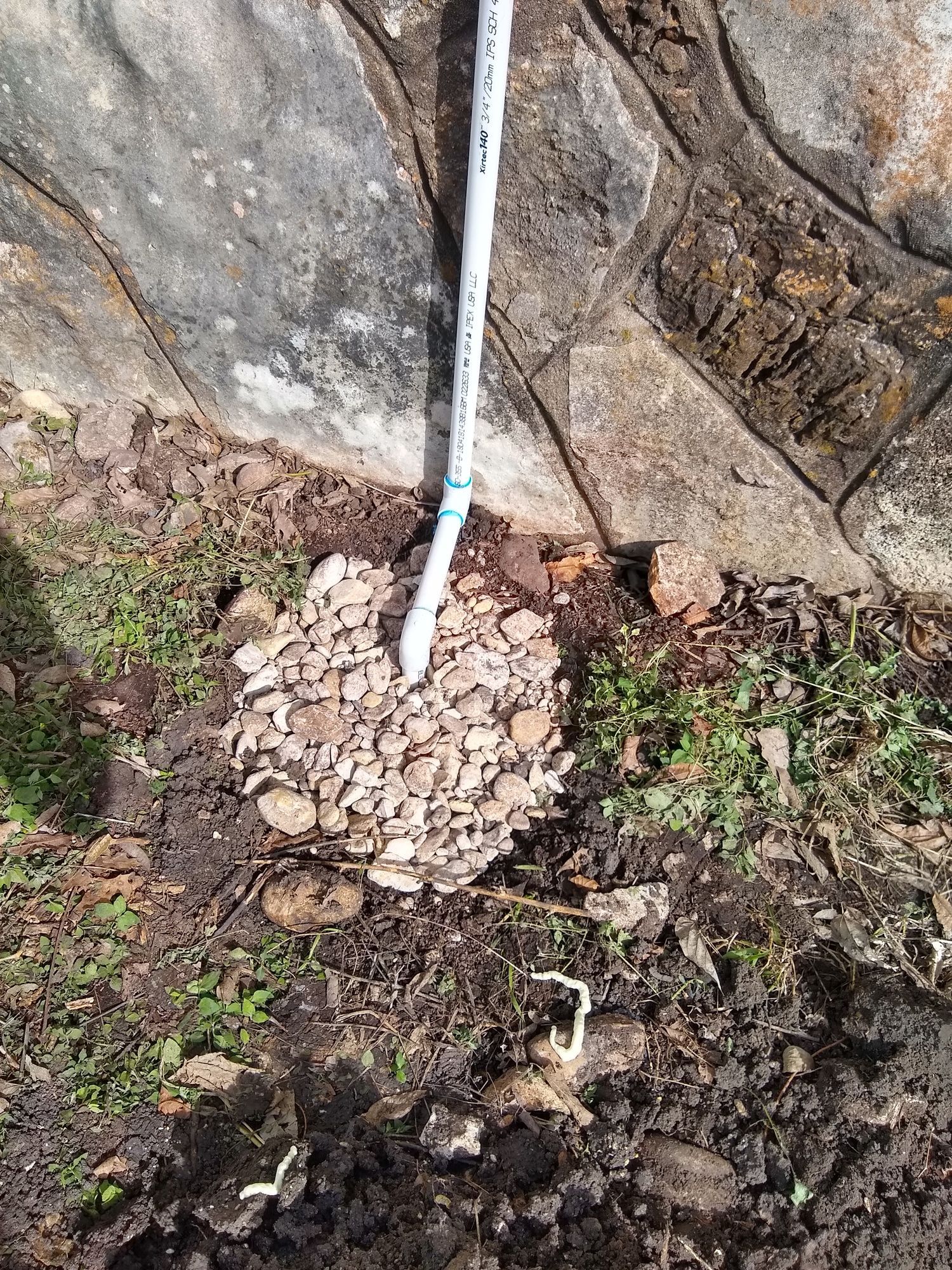 A shovel is sitting in the dirt next to a rock wall.