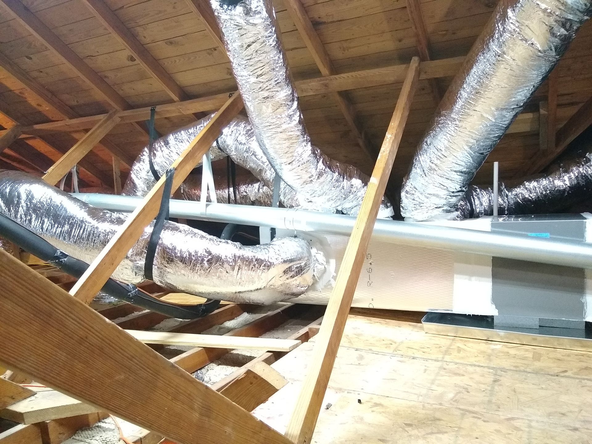 A bunch of ducts are hanging from the ceiling of a building.