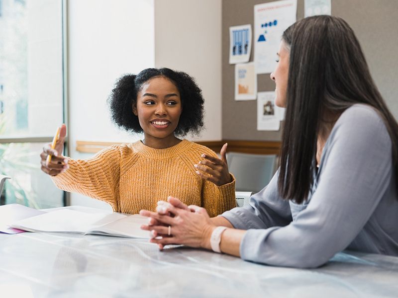 Woman With Curly Hair Talking To Tutor Woman With Curly Hair Talking To Tutor