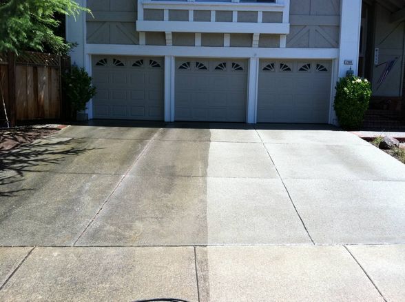 Driveway half cleaned; shows contrast between dirty and clean concrete slabs in front of a three-car garage